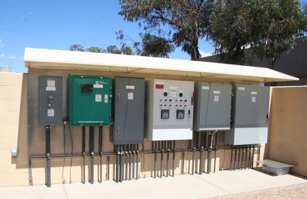 Outdoor electrical panels on a concrete wall.